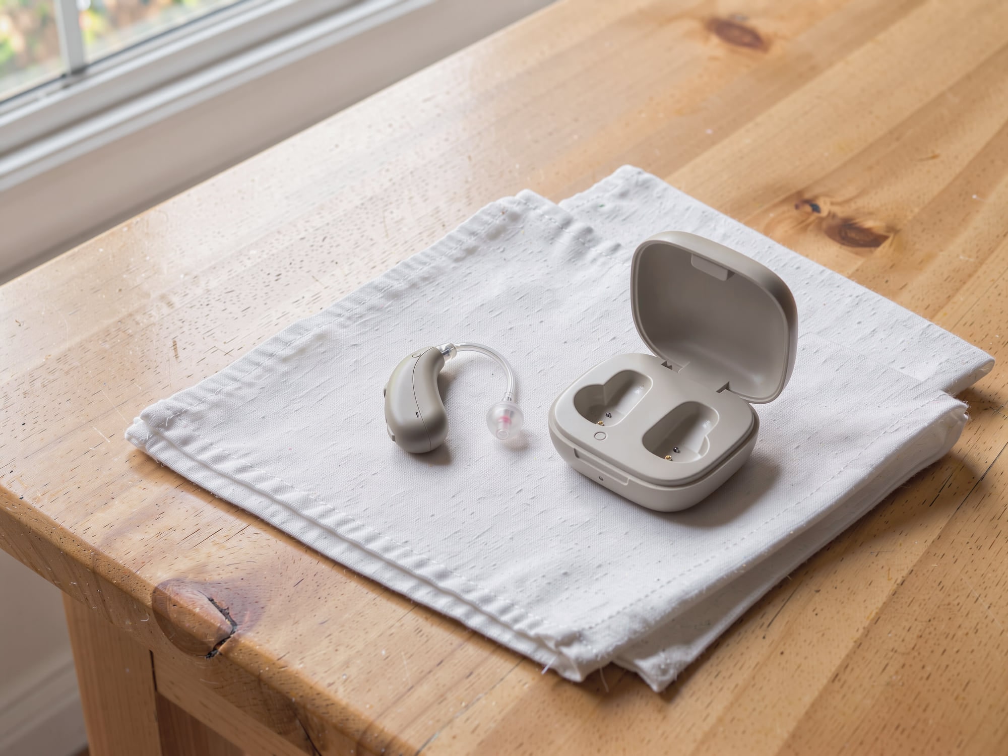 Audífono retroauricular junto a su estuche de carga
